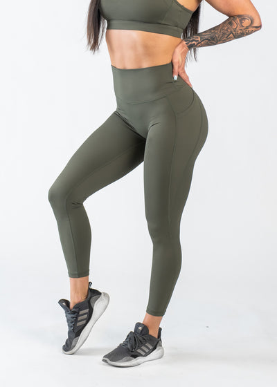 Chest Down 3/4 Front View One Leg Up Wearing Empowered Leggings With Pockets | OD Green